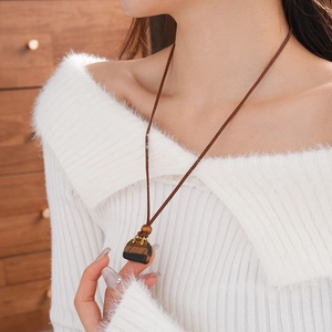 Close-up of a retro faux stone pendant necklace with brown leather cord on a model