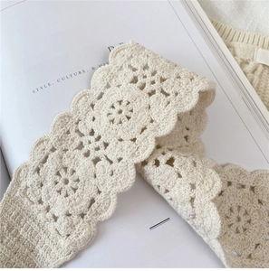 Detail of beige hand-crocheted cotton lace with delicate floral patterns and wavy edges