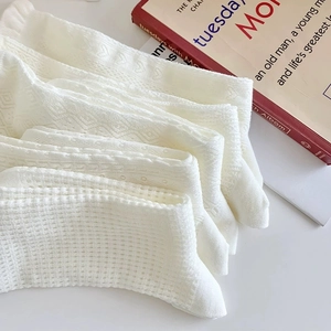 Detail von weißen Baumwollsocken mit Herz- und Rautenmuster in einem Stapel