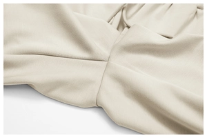Nahaufnahme der präzisen Schrittnaht an aprikosenfarbenen High-Waist-Jogginghosen