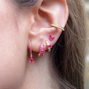 Macro detail of gold-plated earrings set with pink cubic zirconia stones on model