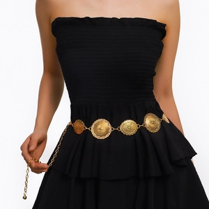 Détail d'une chaîne de taille dorée vintage bohème avec des pendentifs circulaires embossés
