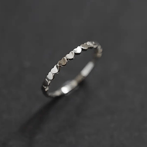 Detailed close-up of polished silver heart-shaped eternity ring on dark grey surface