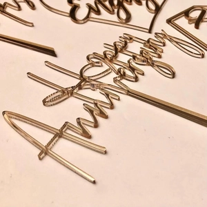 Macro shot of laser-cut acrylic Happy Anniversary cake toppers with smooth edges