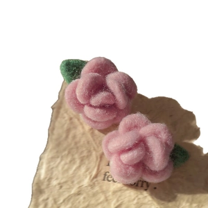 Pink felt wool rose earrings with green leaves on textured paper, handmade floral design