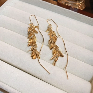 Detail shot of gold leaf tassel earrings on a soft velvet display tray with elegant shine