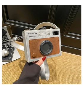 Detail of creative camera-shaped crossbody bag with silver and brown faux leather finish