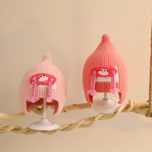 Detail of baby winter knit hats with cartoon doll eyes and soft braided pigtails