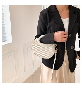 Detail of cream pleated crescent bag with gold hardware and adjustable strap