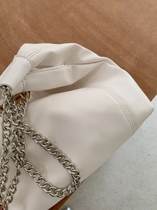 Close-up of white soft leather tote bag with silver chunky chain and pleated detail