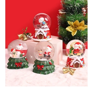 Detailed view of four Christmas snow globes with resin bases on a plush white mat