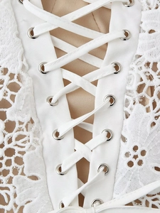 Gros plan détaillé de la robe en dentelle blanche avec œillets métalliques et lacets croisés