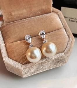 Détail macro de boucles d'oreilles perles champagne et oxydes de zirconium en boîte à bijoux