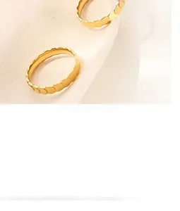 Vue macro de deux bagues minimalistes dorées à bords ondulés sur une base crème