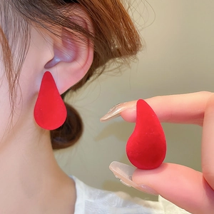 Detail showing elegant red teardrop earrings with a soft velvet flocking texture