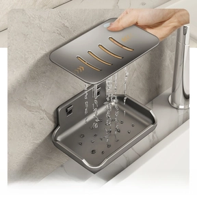 Detail of grey wall-mounted soap dish with removable drainage tray on marble wall