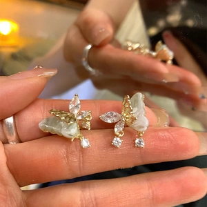 Macro de boucles d'oreilles papillon dorées avec zircons blancs et ailes effet marbre vert