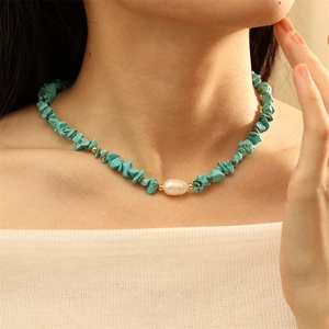 Detailed view of turquoise chip necklace with baroque pearl on a female model