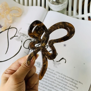 Detail of a brown acetate butterfly hair claw clip held over a fashion magazine