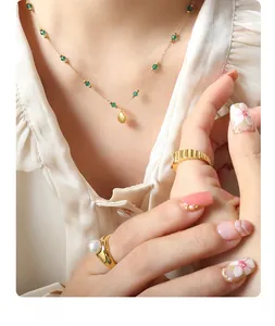 Close-up of gold shell pendant necklace with green beads and pearl rings on a model