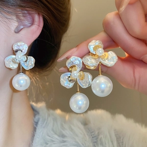 Close-up of gold-plated petal stud earrings with white pearls and elegant floral design