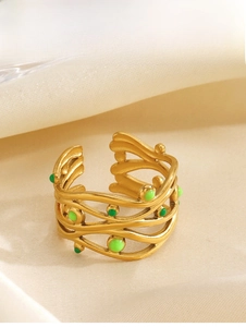 Dettaglio anello incrociato placcato oro 18K con punti di smalto verde su tessuto