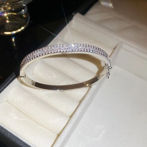 Detail of silver bangle with multi-row zircon pavé setting on white velvet box