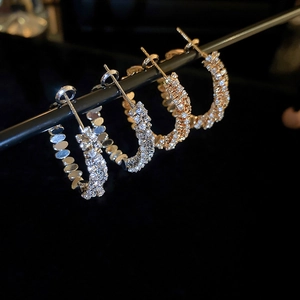 Detailed view of silver and gold C-shaped hoop earrings with zircon pavé setting