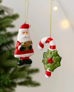 Close-up of ceramic Santa and candy cane ornaments with gold strings on a Christmas tree