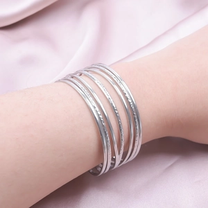 Detail of multi-layer silver stainless steel cuff bracelet with hammered textures on wrist