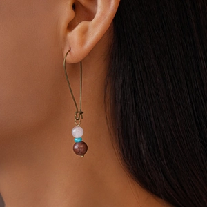 Détail de boucles d'oreilles pendantes avec perles roses et turquoise pour un style rétro