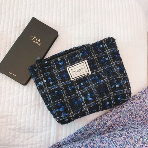 Detail of blue tweed pouch with Time to Party label and zipper on quilted backdrop