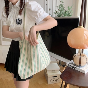 Spacious striped canvas tote bag in beige with purple and green accents in a cozy setting