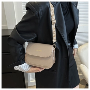 Detail of beige crocodile pattern bag with wide graphic strap and gold hardware