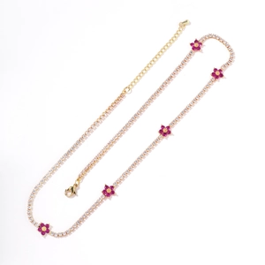Gold tennis chain with purple floral charms and sparkling rhinestones on a white background