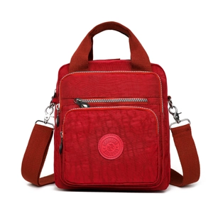 Vue détaillée du sac en nylon rouge imperméable avec poches zippées et logo frontal