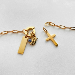 Close-up detail of 14K gold plated titanium steel charms including cross and gemstone.