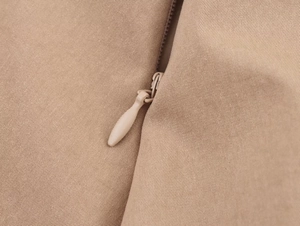 Dettaglio dei pantaloncini in twill beige con cerniera invisibile in tinta unita