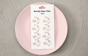 Rose gold bird and elephant shaped paper clips displayed on a pink ceramic plate