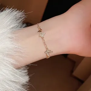 Gold plated butterfly bracelet with zircon and shell charms worn on female wrist