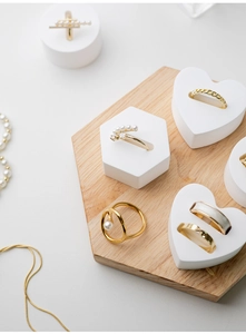 Flat lay of gold rings and pearl jewelry on white geometric display stands and wood