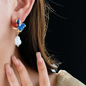 Dettaglio di orecchino vintage con smalto blu e perla barocca indossato da una modella