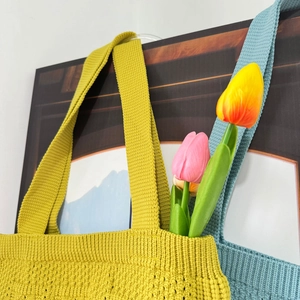 Detail of yellow-green and light blue knitted tote bags with fine textured knit fabric