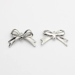 Detail showing polished silver bow pendants with dual connection loops for DIY jewelry
