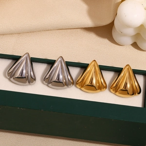 Detailed view of polished gold and silver fan-shaped earrings in a green display case
