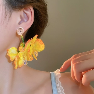 Detail view of yellow fabric floral tassel earrings on model for beach vacation style