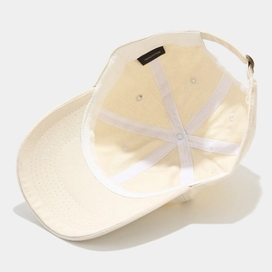 Inside view of cream cotton baseball cap showing 100% cotton label and metal buckle