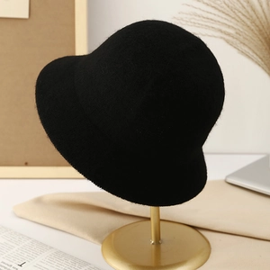 Classic black knitted wool bucket hat for women on a gold stand in a cozy setting