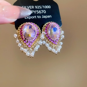 Detail of purple gem earrings with pearls and gold base on a 925 silver jewelry card