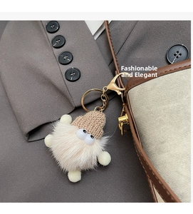 Detail of plush gnome charm with knit hat on a brown leather bucket bag handle